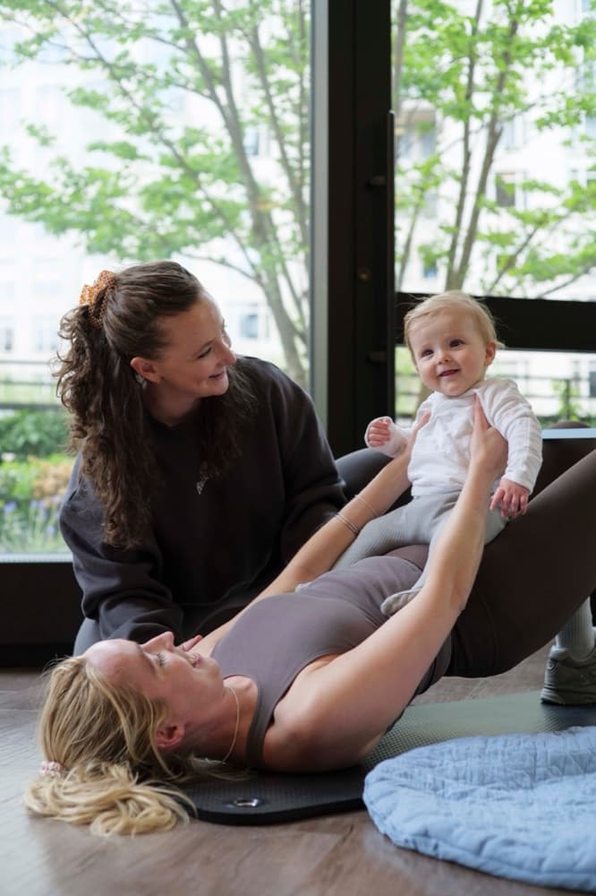 A Woma session — a mother smiling at her baby during a postpartum core exercise